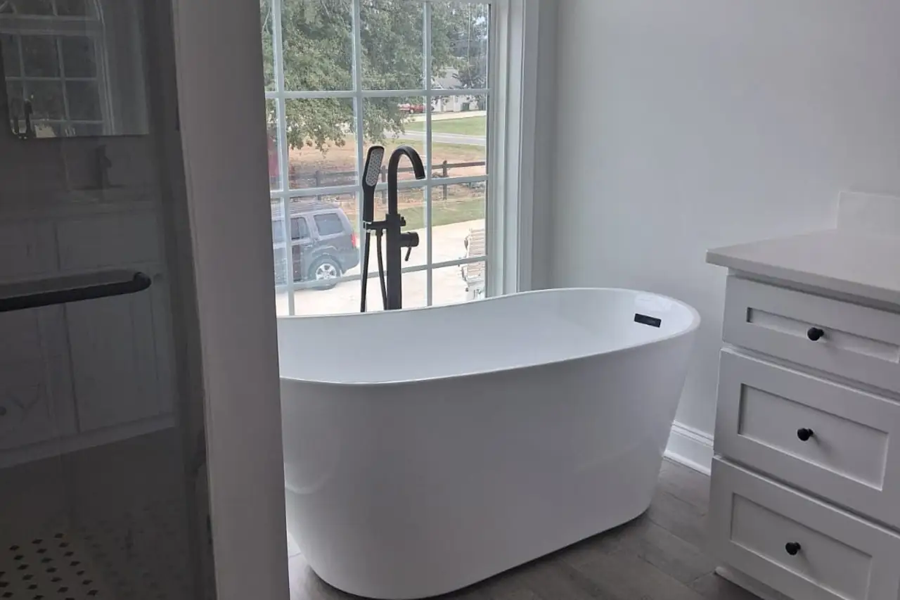 Finished bathroom with a freestanding tub by an arched window