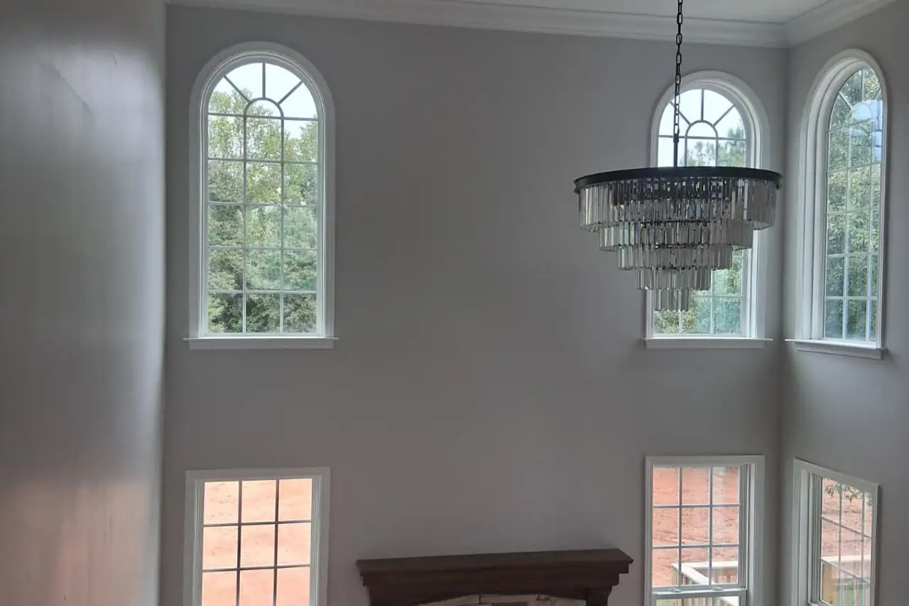 Two-story living room with a chandelier, stone fireplace and hardwood floor